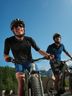 Two men in CRIVIT cycling gear riding mountain bikes on an alpine road