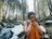 A woman wearing a hat and swimsuit smiles as she dries herself with an orange towel after a cold bath in the winter forest.