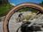 Man in CRIVIT-fietsuitrusting rijdt een e-mountainbike op een rotsachtige alpenweg, omlijst door een wiel