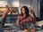 A woman raising a glass of wine at a cozy dinner table, sharing a toast with friends.