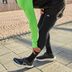 Gros plan sur un étirement des ischio-jambiers en tenue de course CRIVIT sur un chemin pavé.