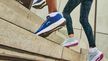 Dos personas suben corriendo escaleras de hormigón con calzado deportivo, haciendo hincapié en el movimiento dinámico y el calzado.
