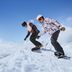 Dos snowboarders descienden juntos por una colina cubierta de nieve, disfrutando del paisaje invernal.