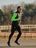Expert Tim loopt op een sportterrein in zwarte en neongroene CRIVIT-hardloopkleding.