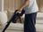Person vacuuming the floor with a SILVERCREST cordless handheld vacuum cleaner in a cozy living room.