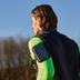 Zijaanzicht van achteren van expert Tim met een zwart CRIVIT functioneel vest, neongroen functioneel shirt en een zak op zijn bovenarm.
