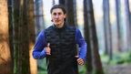 Expert Tim rent door het bos in zwarte en blauwe CRIVIT-hardloopkleding.