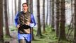 Expert Tim rent in zwarte en blauwe CRIVIT-hardloopkleding door het bos.