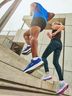 Two people run up concrete stairs in athletic shoes, emphasizing dynamic movement and footwear.