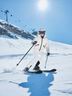 Woman in CRIVIT white ski jacket and helmet skiing on a sunny alpine slope