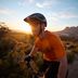 Hombre en bicicleta de montaña con casco y camiseta naranja
