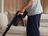 Person vacuuming the floor with a SILVERCREST cordless handheld vacuum cleaner in a cozy living room.