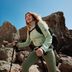 Stefanie Graf, wearing CRIVIT sportswear, looks slightly forward and upward to the side. She smiles, her hands on her hips. The image is cropped, with the CRIVIT key visual in the background.