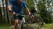Zwei Männer in CRIVIT-Radfahrausrüstung fahren auf einem Waldweg Mountainbike