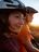 A woman and a man in the picture watching the sunset while wearing a bicycle helmet