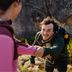 Man reaching out a helping hand to partner while hiking rocky trail wearing CRIVIT softshell jacket and backpack.