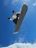 Man in CRIVIT snowboard gear performing a jump against a blue sky