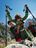 A child with hiking poles is being lifted up by two adults against a mountain backdrop