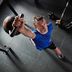 Hombre con ropa de fitness CRIVIT balanceando una kettlebell en el gimnasio