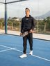 Road cyclist Juan Ayuso from the Lidl-Trek Team stands on a padel court with a padel racket