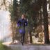 Volledig lichaamsbeeld van expert Tim in zwarte en blauwe CRIVIT-hardloopkleding in het bos.