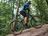 Homme en veste de cyclisme CRIVIT roulant en e-VTT sur un terrain forestier rocheux