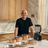 Andre Agassi steht hinter dem Hochleistungsmixer der Signature Edition, Kupfer-Kochgeschirr, Damaststahlmessern und einem Eichenholz-Schneideblock, arrangiert auf einer Küchenarbeitsplatte.
