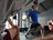 Hombre con camiseta azul CRIVIT levantando una kettlebell en el gimnasio