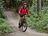 Femme en veste de cyclisme rose CRIVIT roulant en VTT sur un sentier forestier